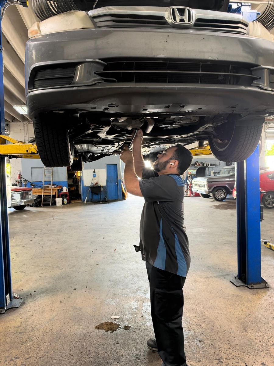ASE certified mechanic inspecting the underside of a car on a lift in Boynton Beach